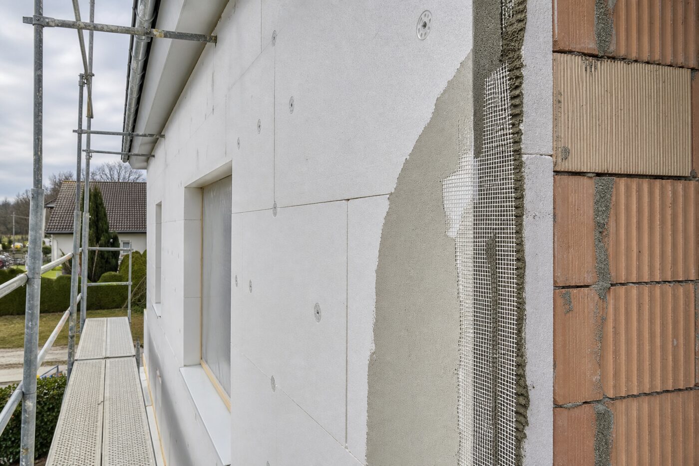 Chantier d'isolation thermique par l'extérieur : panneaux isolants et treillis d'armature en cours de pose.